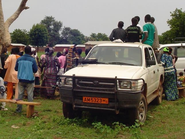 1999 Toyota Hilux in a field with people on the back